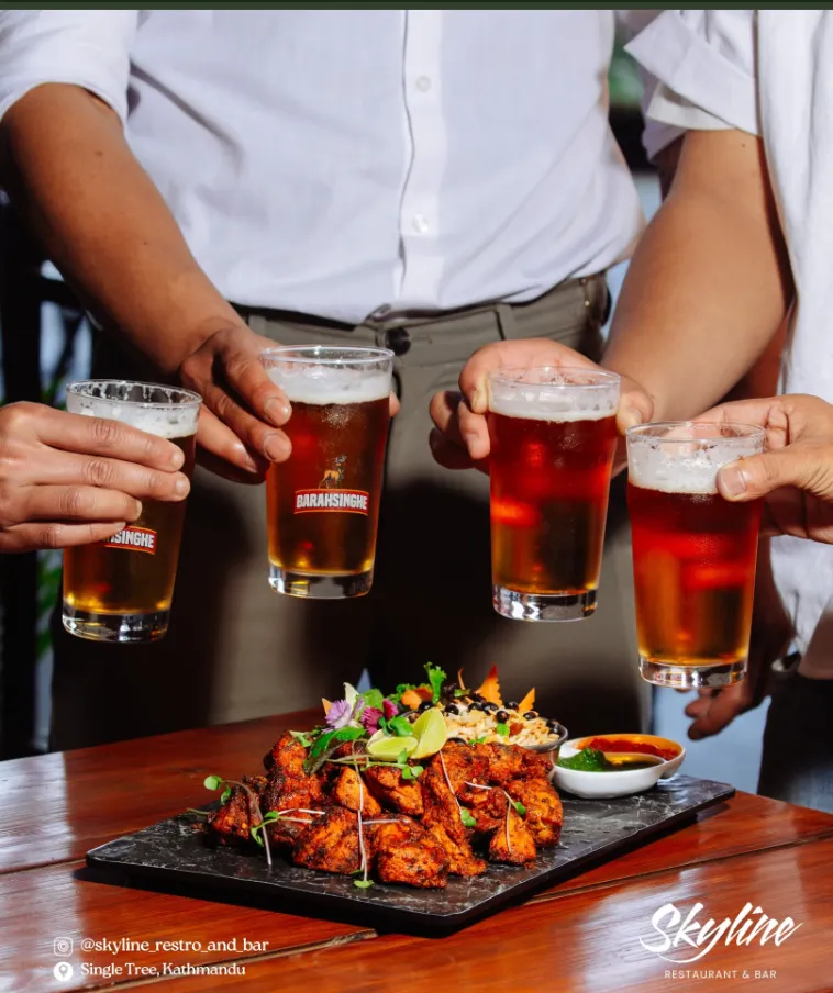 Friends raising glasses of beer over a platter of grilled chicken