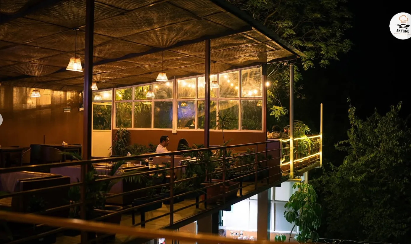 Guests dining on the Skyline terrace at night under warm string lights